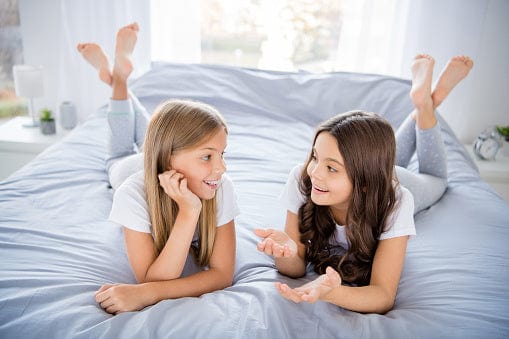 Kinder sitzen fröhlich auf dem Bett mit dem Annabelle’s Topper Kids 7 cm – kindgerechter Komfort und VitaGlow-Bezug für erholsamen Schlaf
