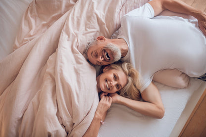 Älteres Paar liegt glücklich auf der Annabelle’s SleepShield Auflage – erholsamer Schlaf mit Schutz vor Elektrosmog